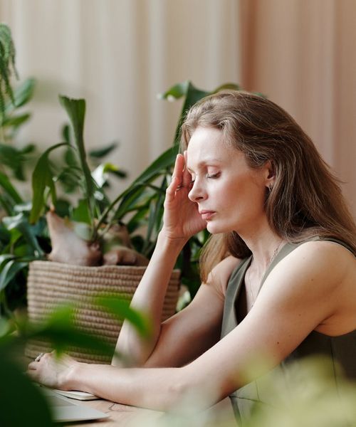 Woman with a serene expression lightly touching her temple.